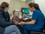 Female doctor having a consultation with a smiling young child and mother